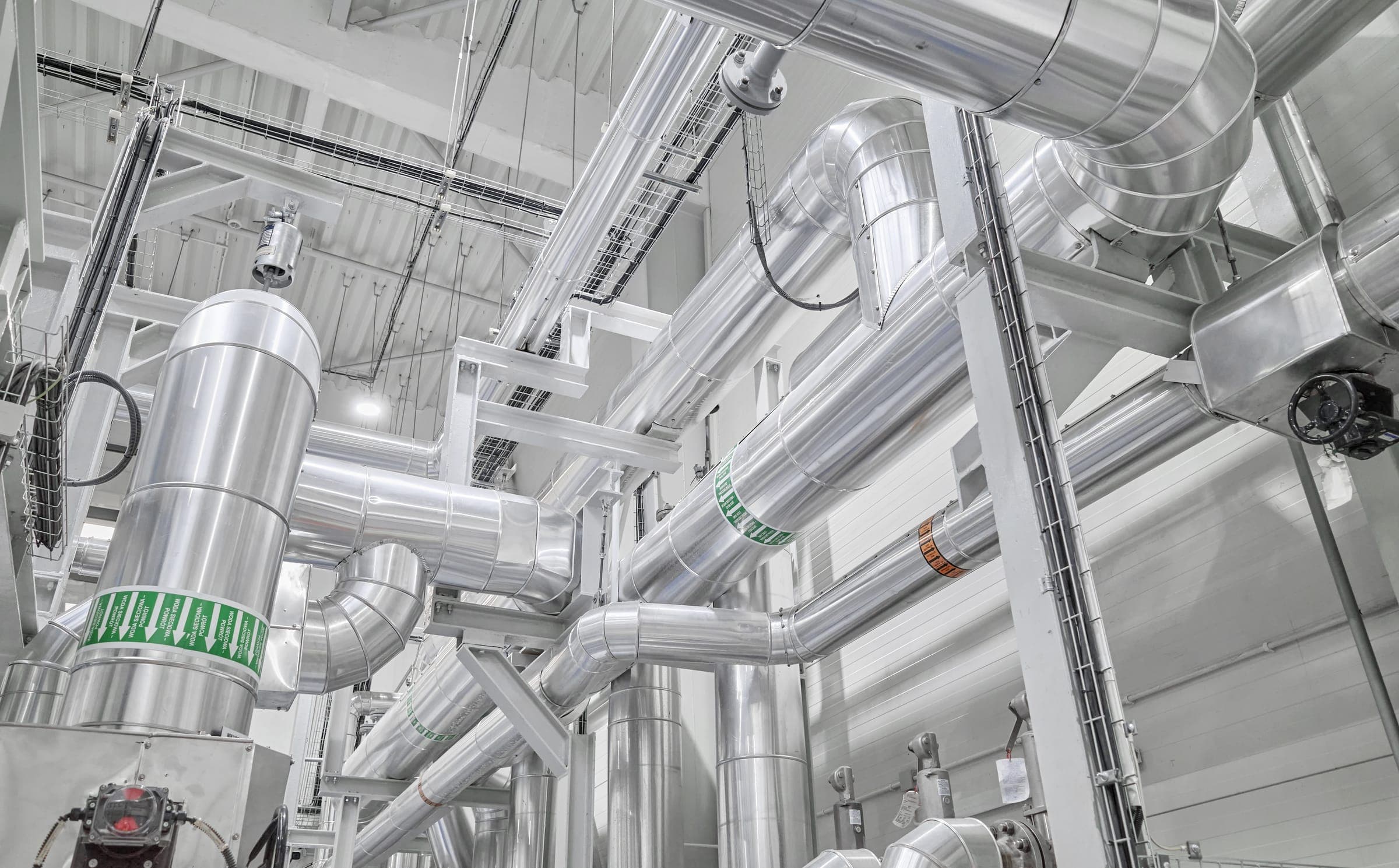 A mechanical plantroom, with pumps, headers and insulated primary pipework running at high level.