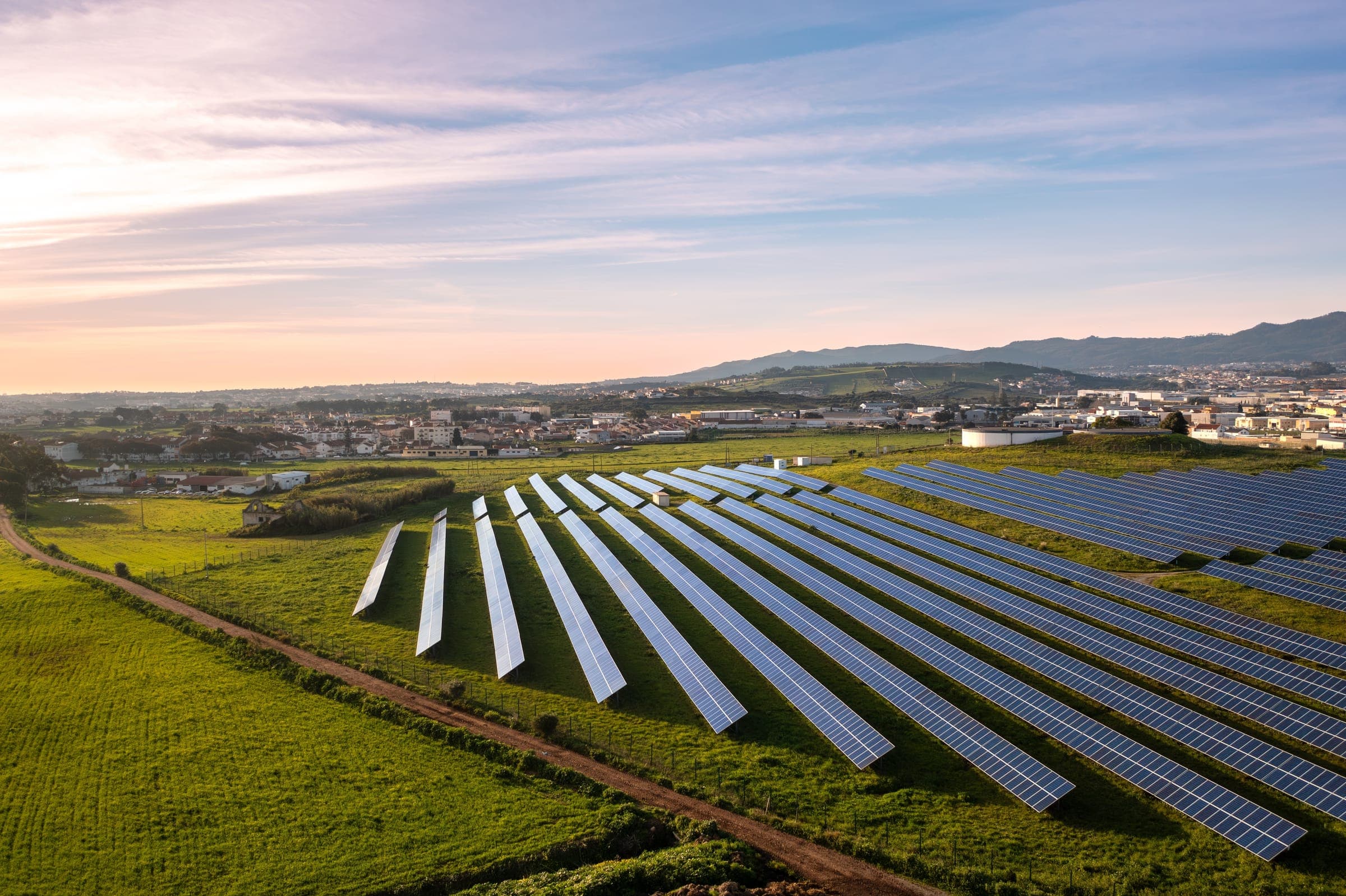 Rows of ground-mounted photovoltaic panels in an open field.